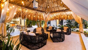 An outdoor seating area with wicker furniture and a thatched roof. - Bocobay Wariruri Condos (Noord)