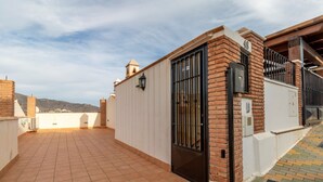 A rooftop terrace with a tiled floor, a gated entrance, and a view of the surrounding landscape. - Balcony with Sea View in Lambda 1 Apartment (Almuñécar)