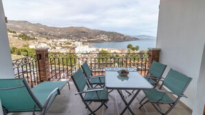 A balcony with a table and chairs, overlooking a coastal town and hills. - Balcony with Sea View in Lambda 1 Apartment (Almuñécar)