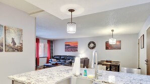 A modern kitchen with a granite countertop, stainless steel sink, and a dining area with a table and chairs.