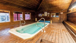 A wooden interior with a hot tub, wooden flooring, and windows.