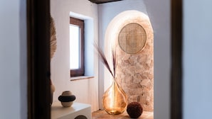 Un intérieur chaleureux avec un mur en pierre, un panier rond en osier et un vase contenant des roseaux séchés.