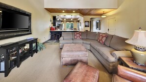 A spacious living area with a large flat-screen TV, a sectional sofa, and a wooden ceiling. - Two levels | Gas fireplace | Walk to ski slopes (Brian Head)