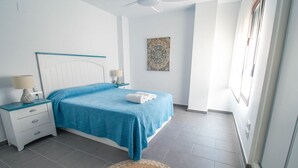 A bedroom with a bed, nightstands, a lamp, a wall art piece, and a window. - Apartment Oasis of Salobreña Gym and Balcony (Granada)