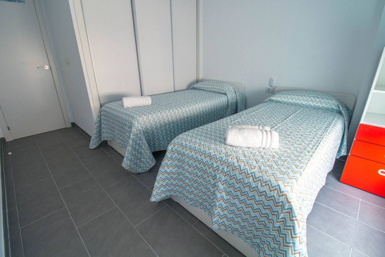 Una habitació amb dos llits individuals, cadascun amb un estovat estampat i una tovallola blanca sobre el llit.