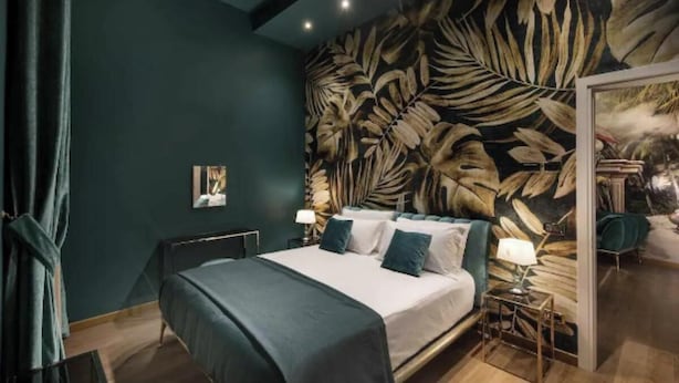A modern bedroom with a large bed, dark walls, and a leaf-patterned mural. - Charming Canal View Apartment in Historic Venetian Palace







 (Venezia)
