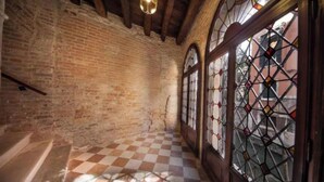 A corridor with checkered flooring, brick walls, and stained glass windows. - Charming Canal View Apartment in Historic Venetian Palace







 (Venezia)
