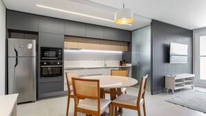 Eine moderne Küche mit einer zentralen Kochinsel, integrierten Geräten und einem Essbereich mit Holzkästen.