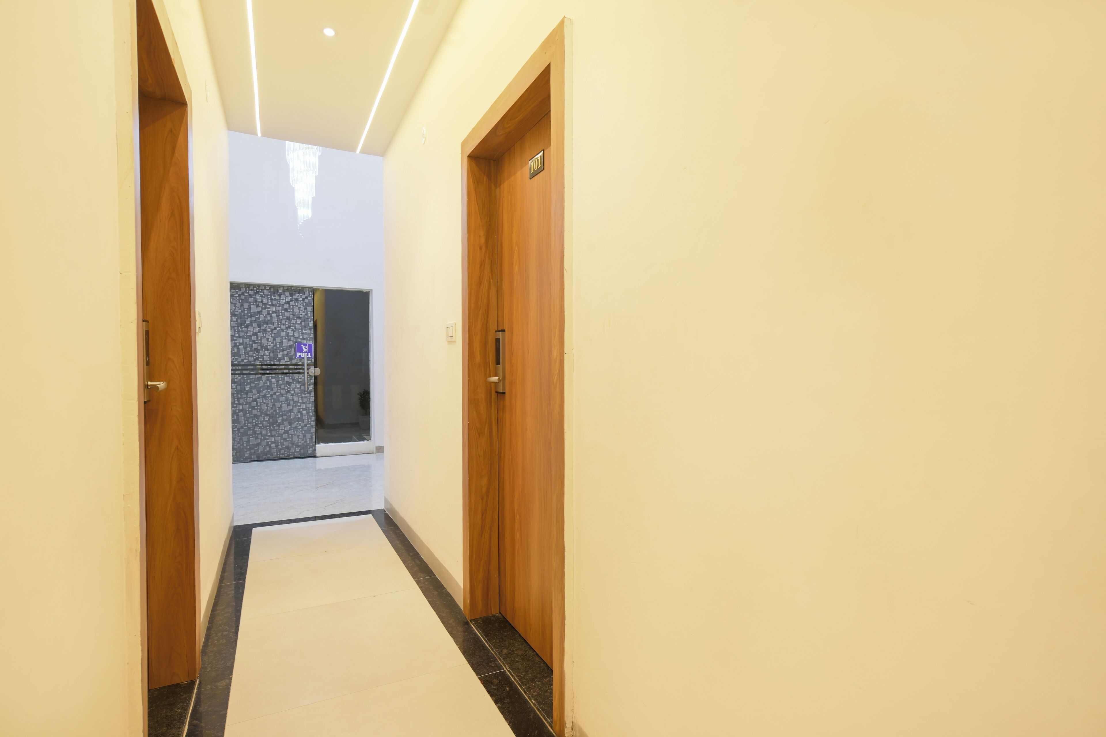A hallway with wooden doors, a tiled floor, and a wall with a textured pattern.