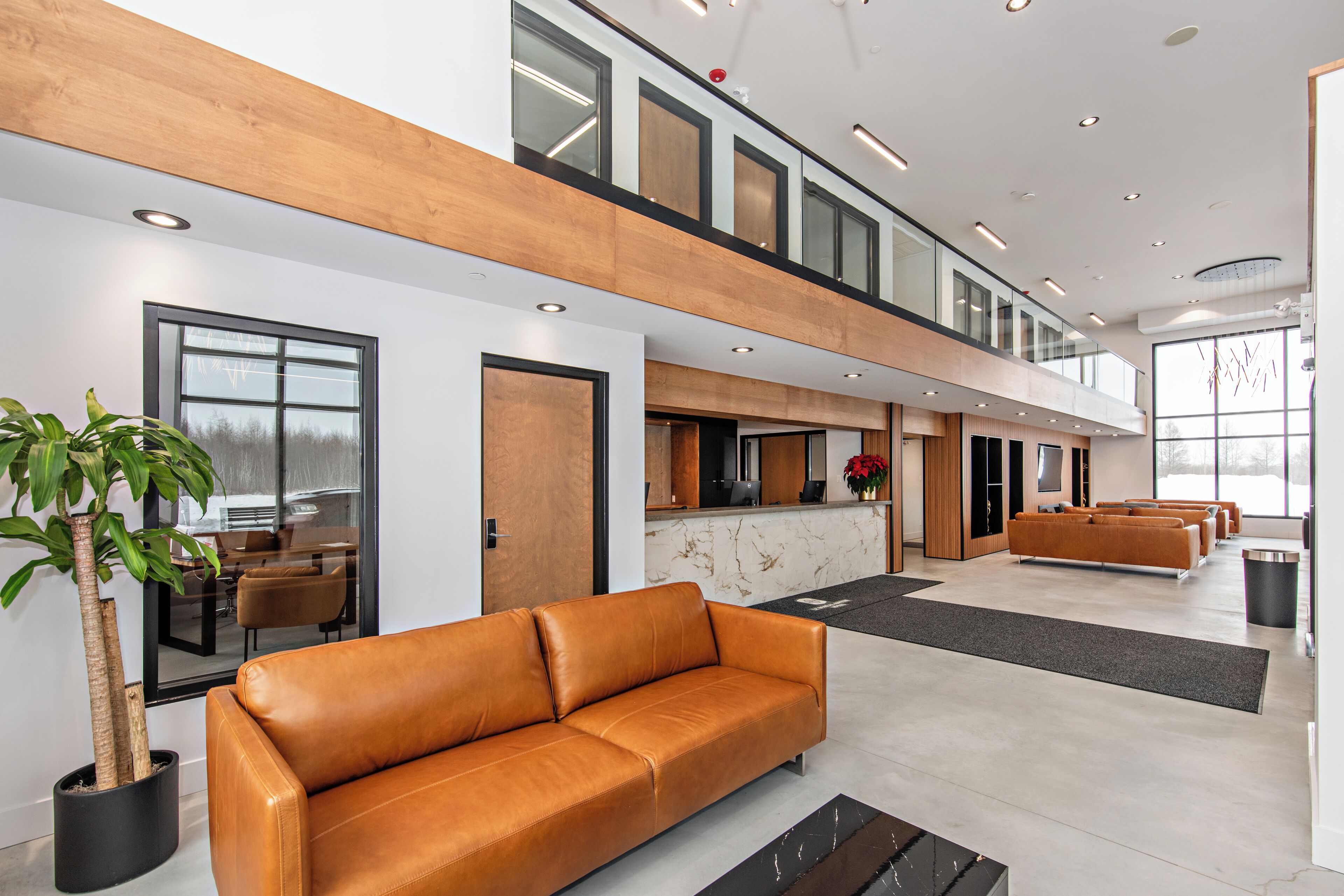 A modern lobby with a leather sofa, a reception desk, and a staircase.