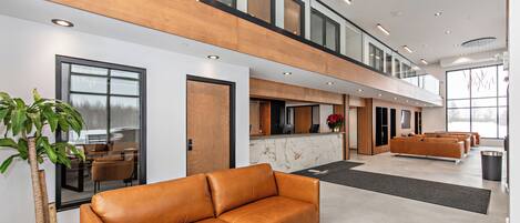 Een moderne lobby met een leren bank, een receptiebalie en een trap.