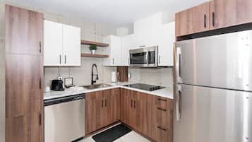 A modern kitchen with wooden cabinets, stainless steel appliances, and a marble countertop.