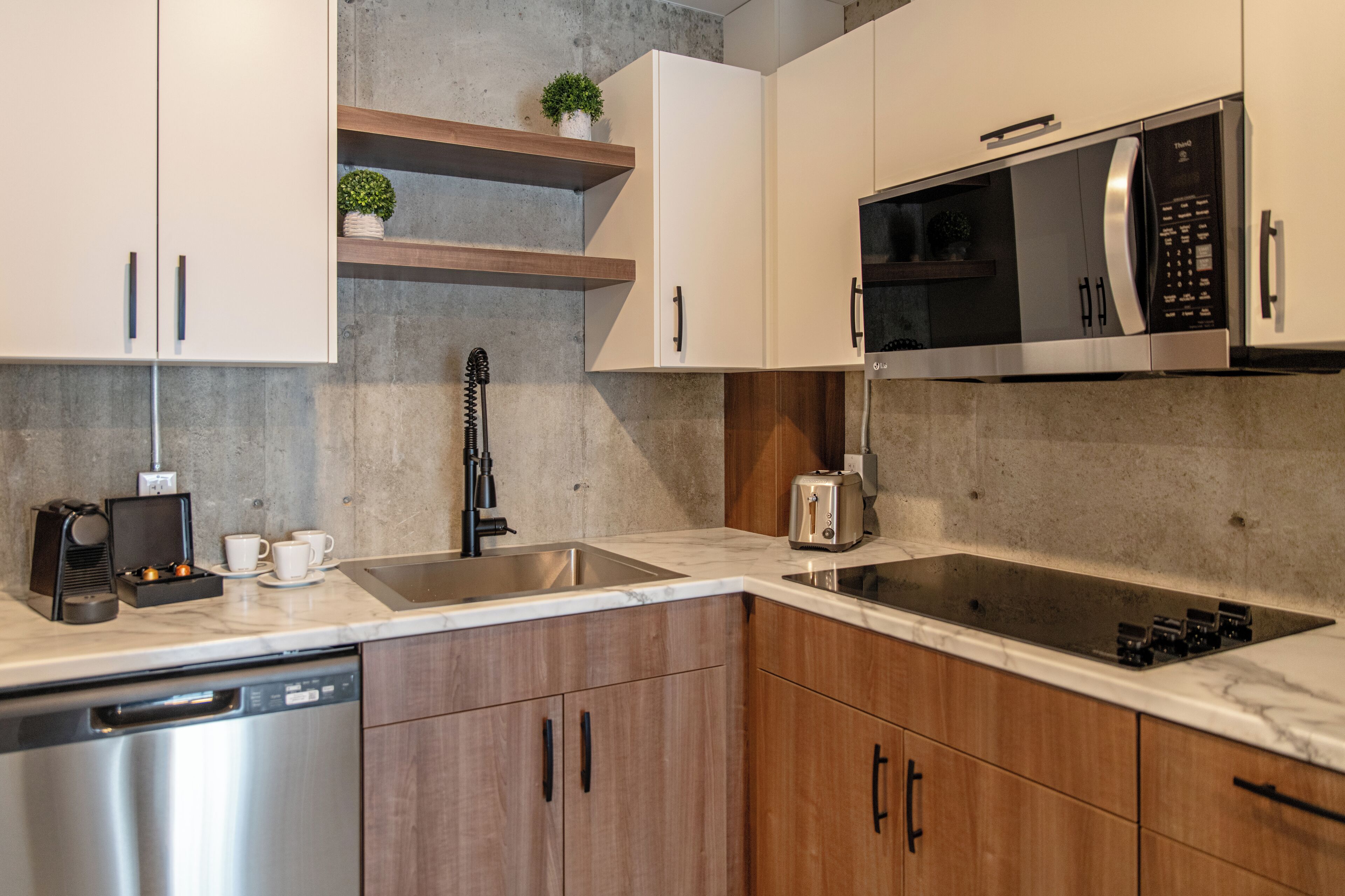 A modern kitchen with a dishwasher, microwave, toaster, and a built-in stove.