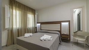 A modern hotel room with a large bed, a bedside table, a chair, and a mirror. - Jolanda Sea Breeze (Trapani)