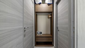 Ein schmaler begehbarer Kleiderschrank mit Holztüren, einem eingebauten Regal und einer Kleiderstange.