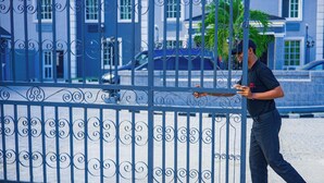 A man walking past a blue metal fence with decorative patterns. - Great Western Hotel and Suites (Owerri)