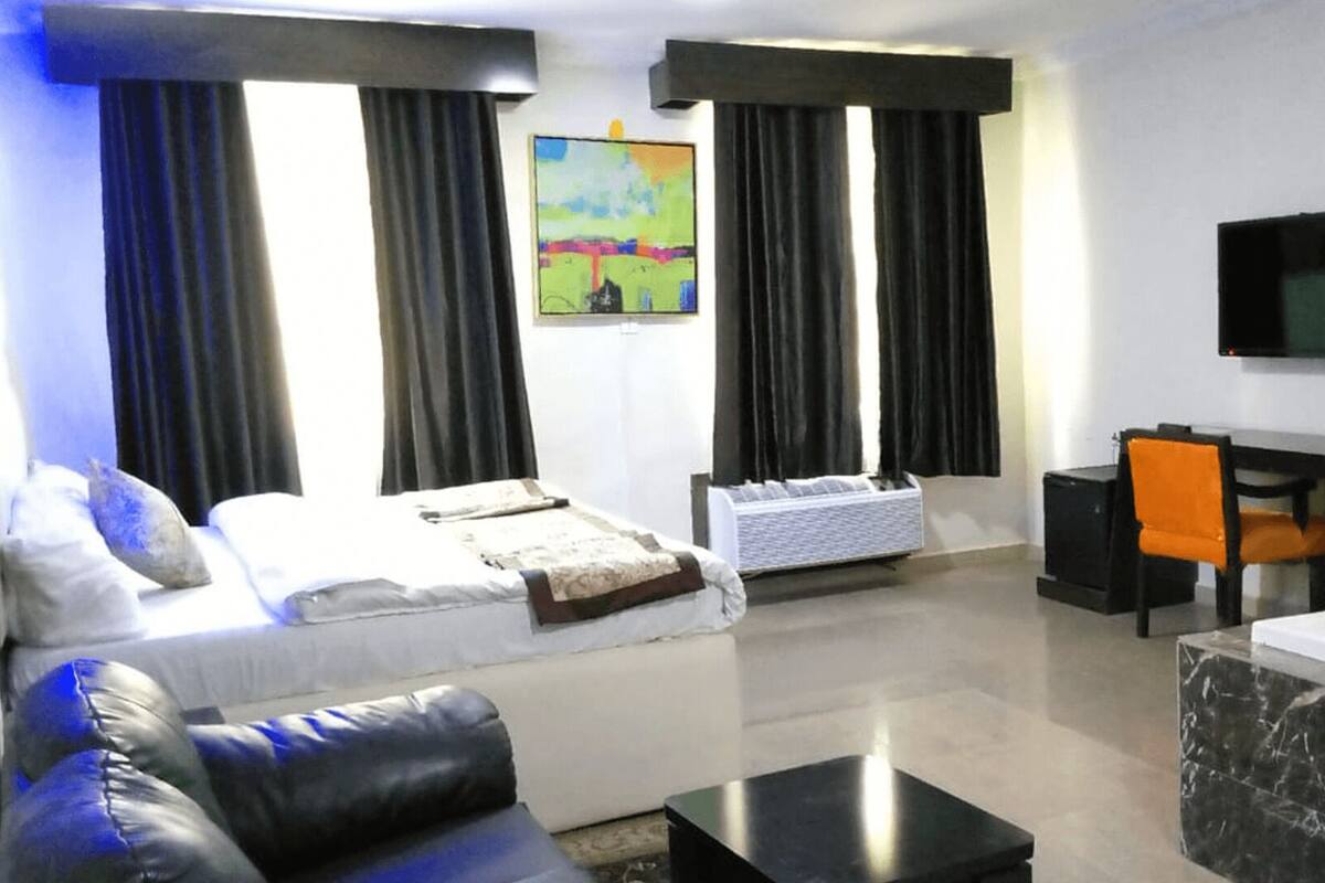 Una moderna camera d'albergo con un letto, un divano, una scrivania e una televisione.