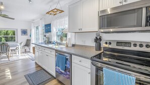 A modern kitchen with white cabinetry, stainless steel appliances, and a granite countertop. - Reese's Beach Retreat on beautiful Anna Maria Island (Holmes Beach)