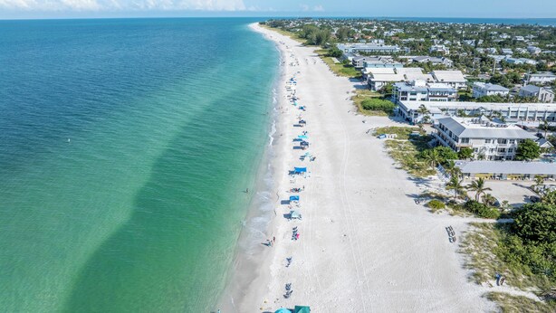 An aerial view of a beach with a row of beachside houses and a clear blue ocean. - Reese's Beach Retreat on beautiful Anna Maria Island (Holmes Beach)