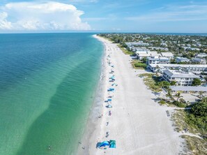 An aerial view of a beach with a row of beachside houses and a clear blue ocean. - Reese's Beach Retreat on beautiful Anna Maria Island (Holmes Beach)