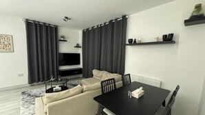 A modern living room with a sofa, a TV, a dining table, and a coffee table.