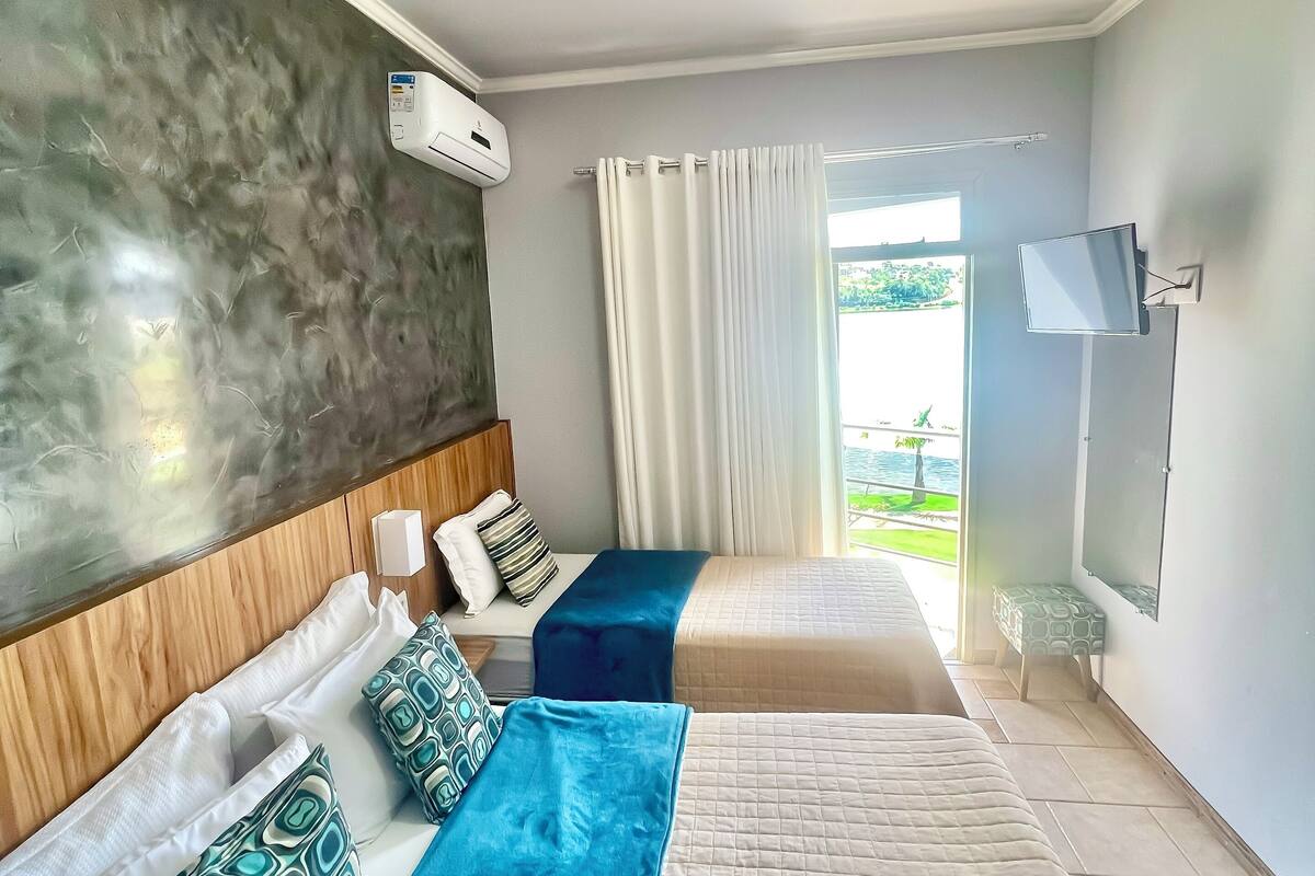 Ein Hotelzimmer mit zwei Betten, einem Fernseher, einer Klimaanlage und Blick ins Freie.