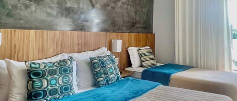 A hotel room with two beds, a large window with curtains, an air conditioning unit, and a textured wall.