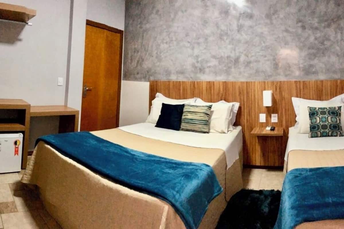 Ein Hotelzimmer mit zwei Betten, einem Schreibtisch und einem kleinen Kühlschrank.