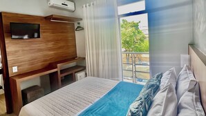 A hotel room with a bed, a desk, a TV, and an air conditioning unit. - Lara's Hotel (Capitólio)