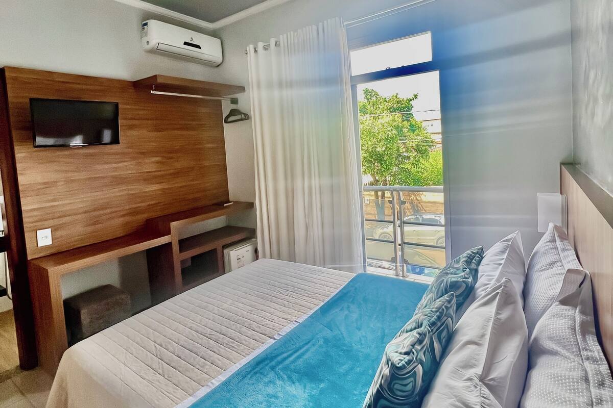 Ein Hotelzimmer mit Bett, Schreibtisch, Fernseher und Klimaanlage.