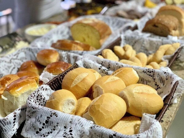 A variety of bread and pastries displayed in baskets and on a table. - Lara's Hotel (Capitólio)