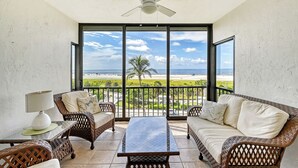 A balcony with wicker furniture, a ceiling fan, and a view of the beach. - Best View on Siesta Key 1 Bed 1 Bath Top Floor Steps to Beach (Siesta Key)