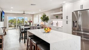 Una cocina moderna con una isla grande, electrodomésticos de acero inoxidable y vistas al exterior.
