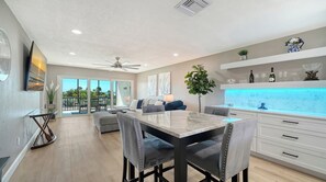 A modern kitchen with a dining area, a ceiling fan, and a view of the outdoors.