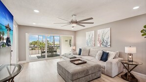 Un salón amplio con un gran ventanal, ventilador de techo y vistas al exterior.