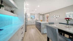 A modern kitchen with a marble countertop, built-in appliances, and a dining area with a marble table and chairs.