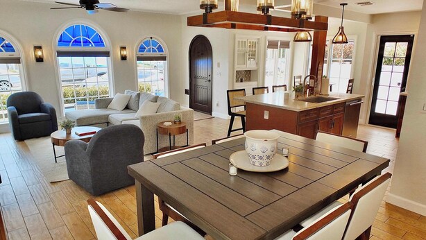 A spacious living area with a dining table, comfortable seating, and a view of the outdoors through large windows. - Belmont Shore Beach House (Long Beach)