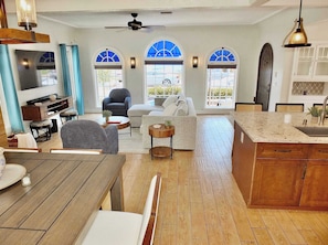 A spacious living area with a dining table, sofas, and a kitchen with a large island.
