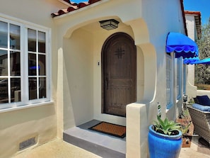 A house with a large wooden door, a window, and a blue awning.