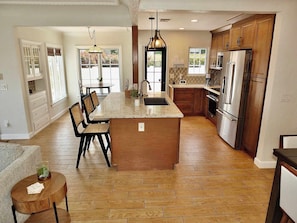 A spacious kitchen with a central island, wooden cabinets, and a dining area with chairs.