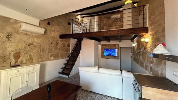 A modern kitchen with a stone wall, a wooden staircase, and a white sofa. - Alghero my Love (Alghero)