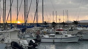 A marina with multiple boats docked, a sunset in the background, and a clear sky. - Alghero my Love (Alghero)