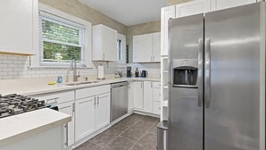 A modern kitchen with white cabinets, stainless steel appliances, and a tiled backsplash.