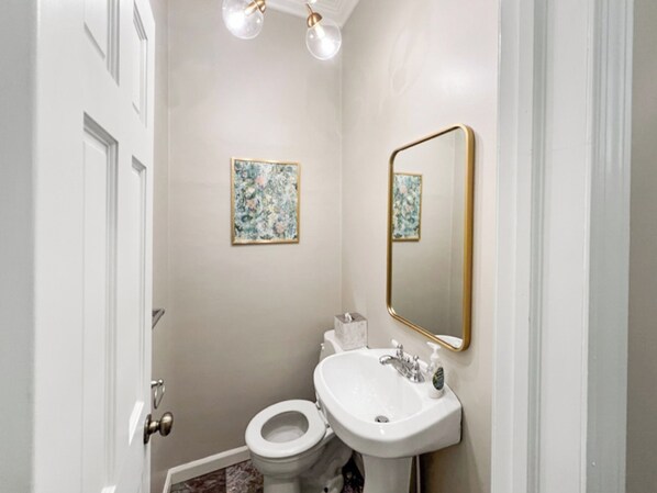 Un baño con inodoro, lavamanos y dos cuadros con motivos florales en la pared.