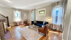Un salon spacieux doté de parquets, d’un ensemble de canapés, d’une table basse et d’un escalier.