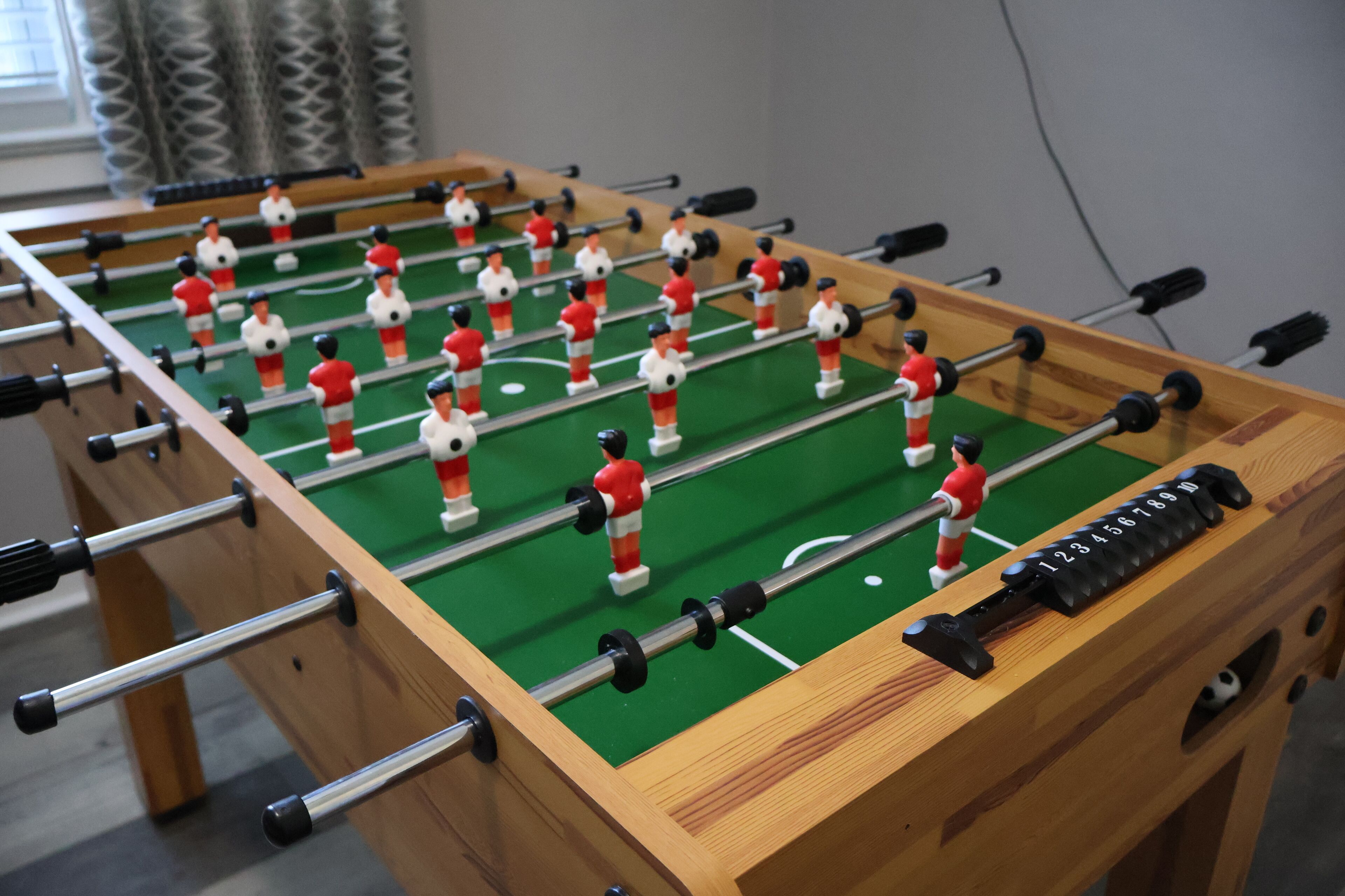 Een tafelvoetbaltafel met meerdere spelers en een telmechanisme.