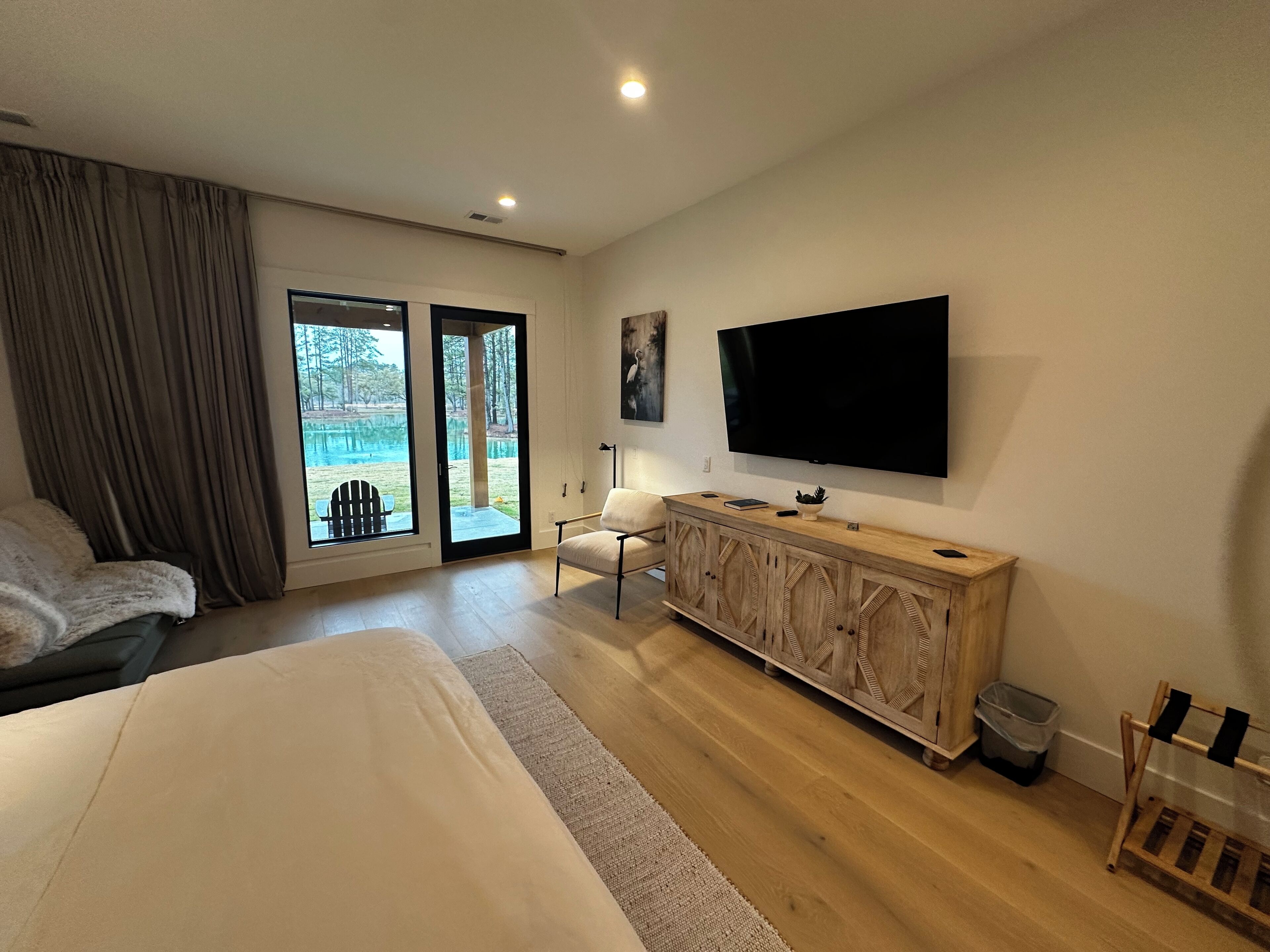 Une chambre d’hôtel moderne dotée d’un grand lit, d’une armoire en bois, d’un téléviseur à écran plat et d’une porte-fenêtre coulissante donnant sur un espace piscine.