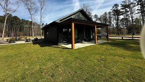 A modern building with a covered patio area, surrounded by a well-maintained lawn and trees. - Egret Cottage Suite    3715-B (WALTERBORO)