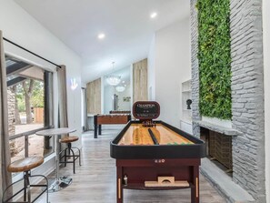 A pool table in a room with a stone wall and a green wall feature.