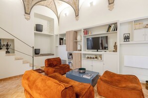 Un salon avec une cheminée, un téléviseur et un escalier.